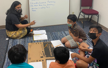 A teacher leading a small group of early-grade students in a classroom lesson