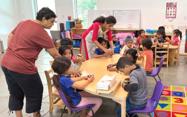 Pre-school children working with hands-on materials at a table with their teachers