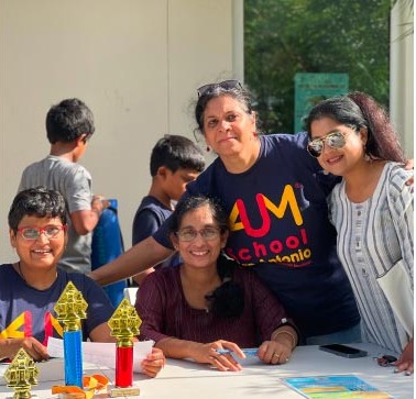 Aum School families and teachers smiling together at a community event