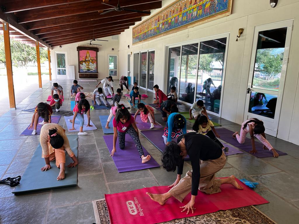 Children and an instructor practicing yoga together on colourful mats outdoors