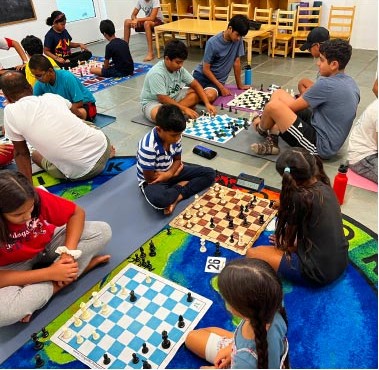 Students playing chess together during an Aum School summer camp session