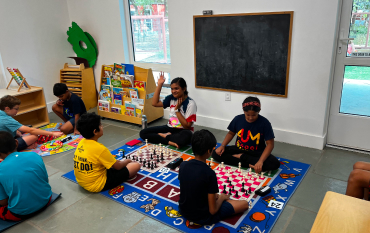 Students sitting in a circle playing chess and learning games in a bright classroom